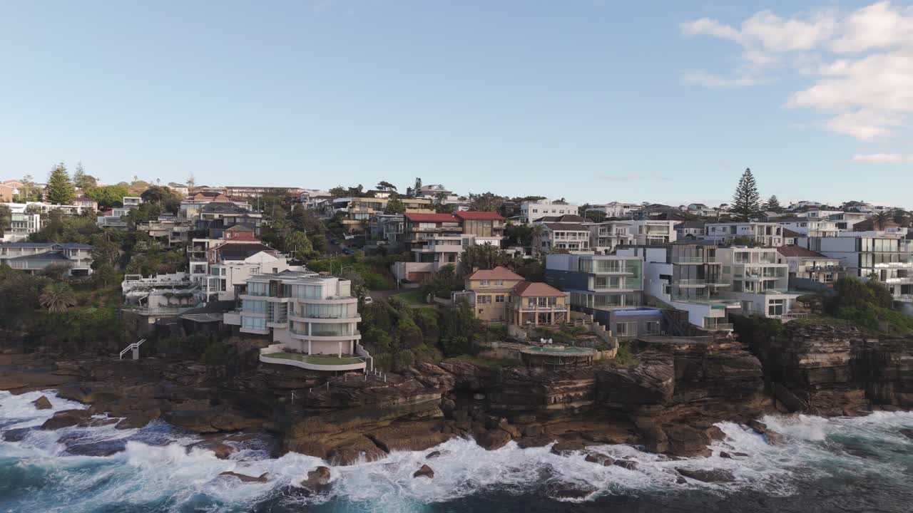 Aerial slide right of luxury cliffside home with ocean views – upscale waterfront property in Sydney’s Eastern Suburbs, Australia.