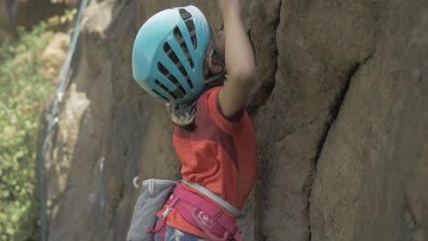 Close-up-shot-of-an-8-year-Asian-girl-rock-climbing-in-the-outdoors,-Tracking-shot