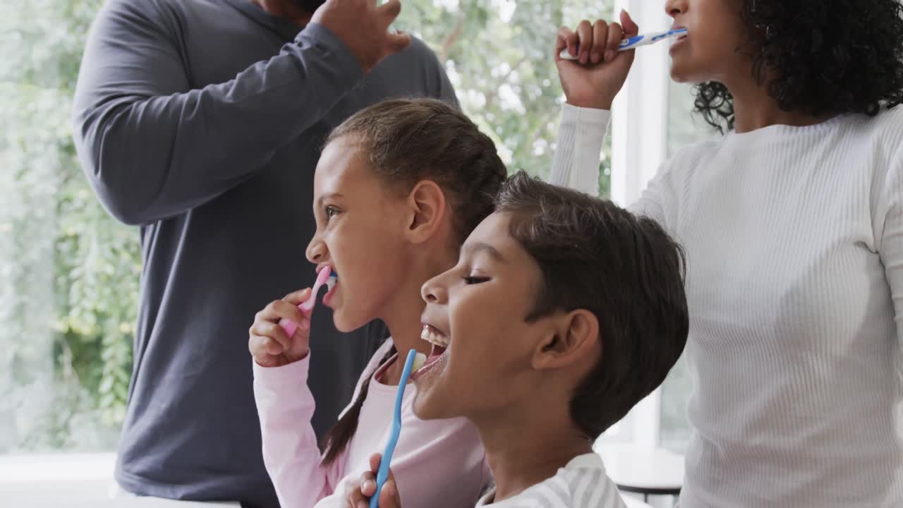 두 인종의 형제와 자매가 행복한 커플과 함께  ⁇ 빛이 나는 욕실에서 치아를  ⁇ 고, 느린 움직임