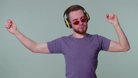 cheerful attractive man listening music via headphones and dancing disco fooling around having fun