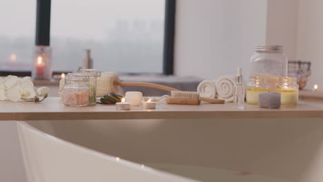 la caméra se concentre sur une baignoire blanche avec de l'eau et une table en bois avec des éléments de salle de bain 1