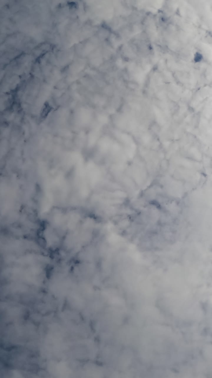 Rainy cloudscape formation in the atmosphere. Cirrus clouds covering the blue sky. Low angle view. Vertical video