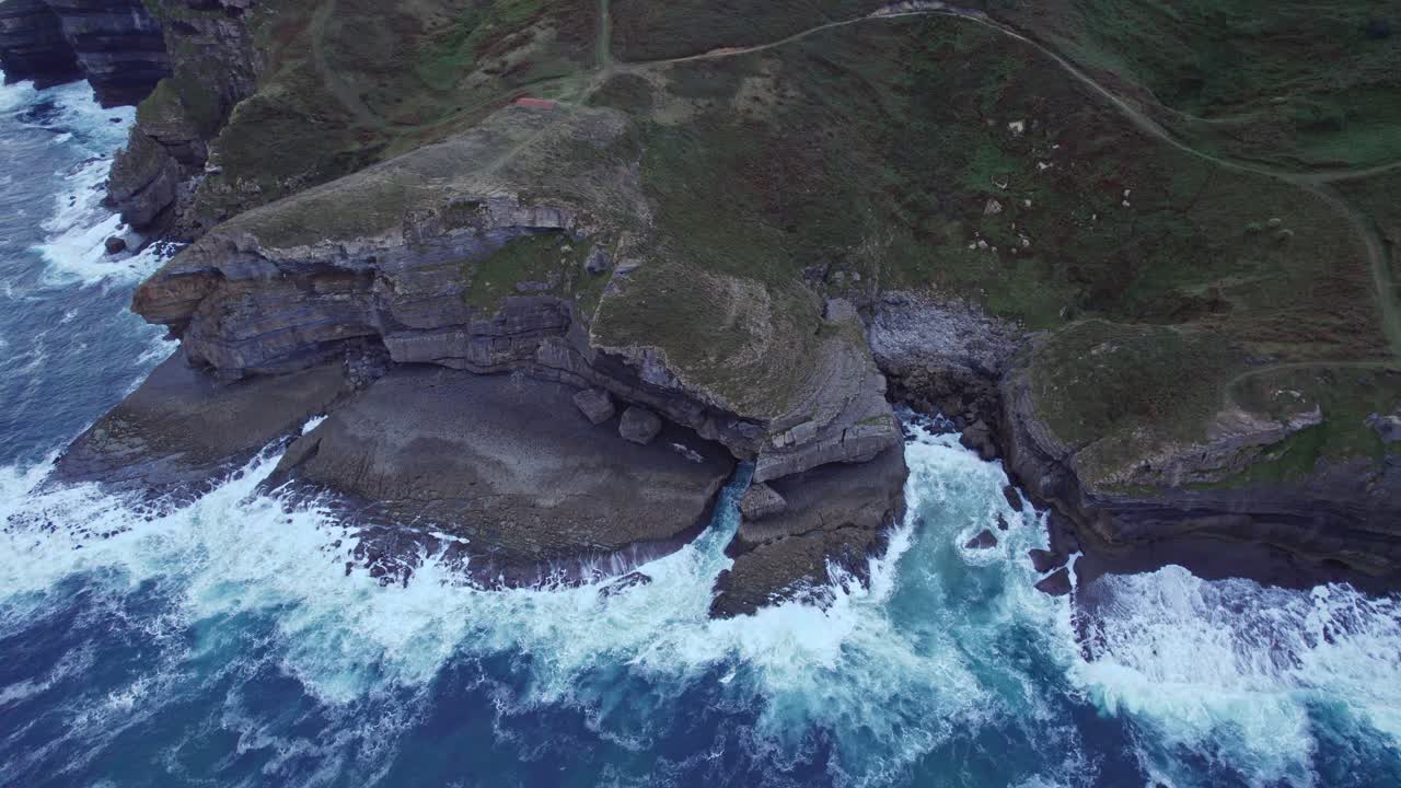drone captura el borde rocoso de isla isla donde las olas del mar cantábrico azul chocan