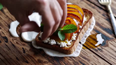 preparing gourmet toast with peaches, ricotta, honey, and mint