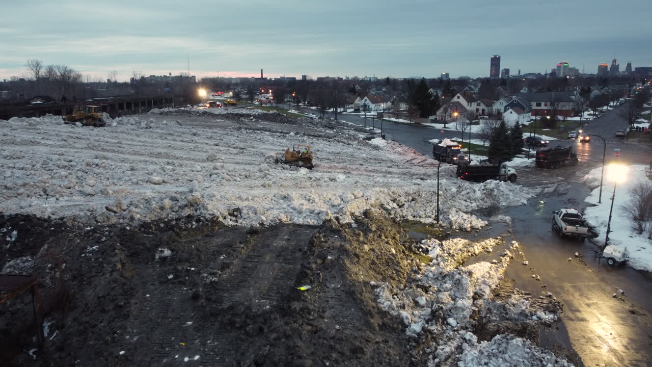 toma nocturna aérea de camiones que descargan el exceso de nieve en el sitio de almacenamiento en buffalo, nueva york