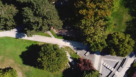 2-4-Modern-futuristic-circlular-shaped-park-birds-eye-view-aerial-rise-over-empty-dry-water-fountain-pool-across-restricted-childrens-park-during-COVID-19-pandemic-social-distancing-city-bus-hub-paths