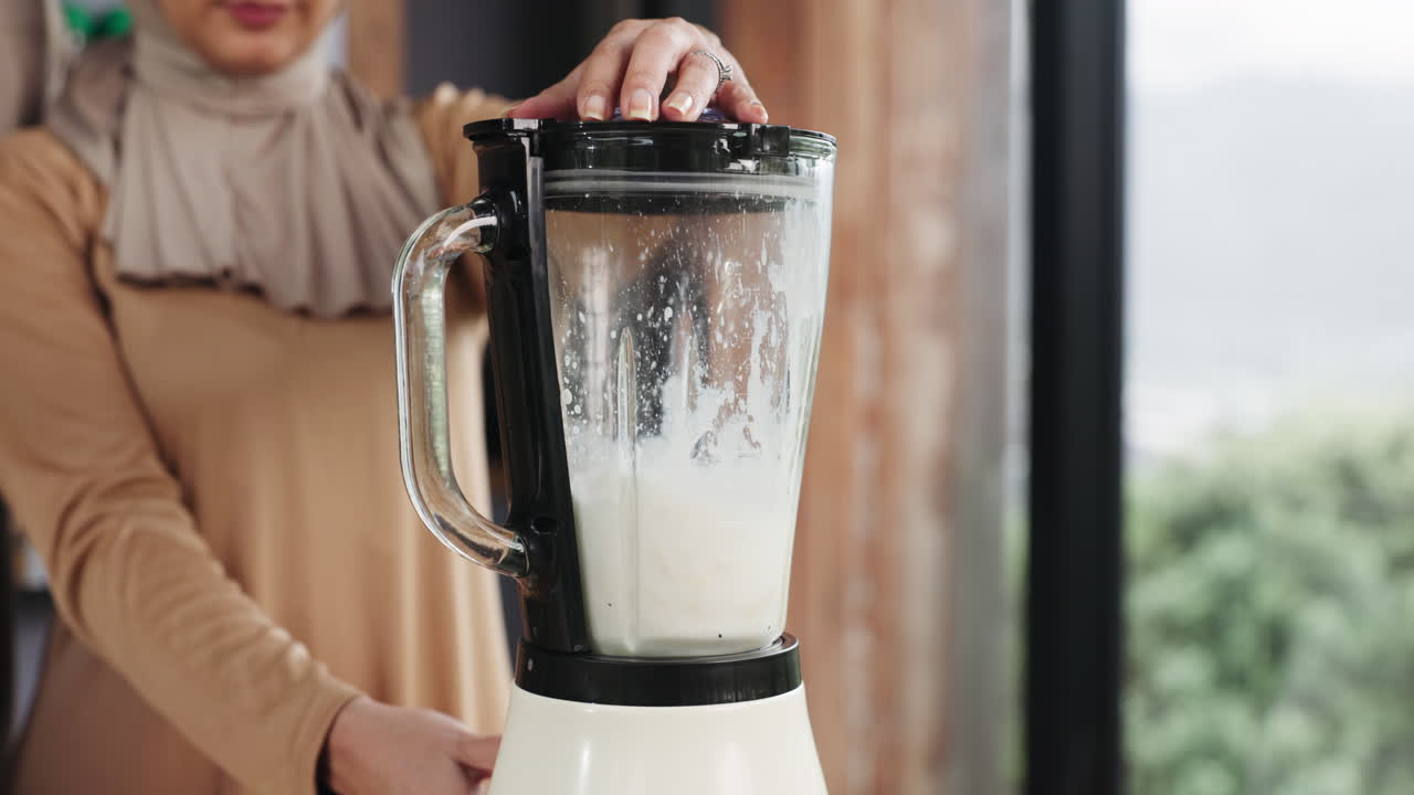 Primo piano di un frullatore che mescola un frullato bianco in cucina