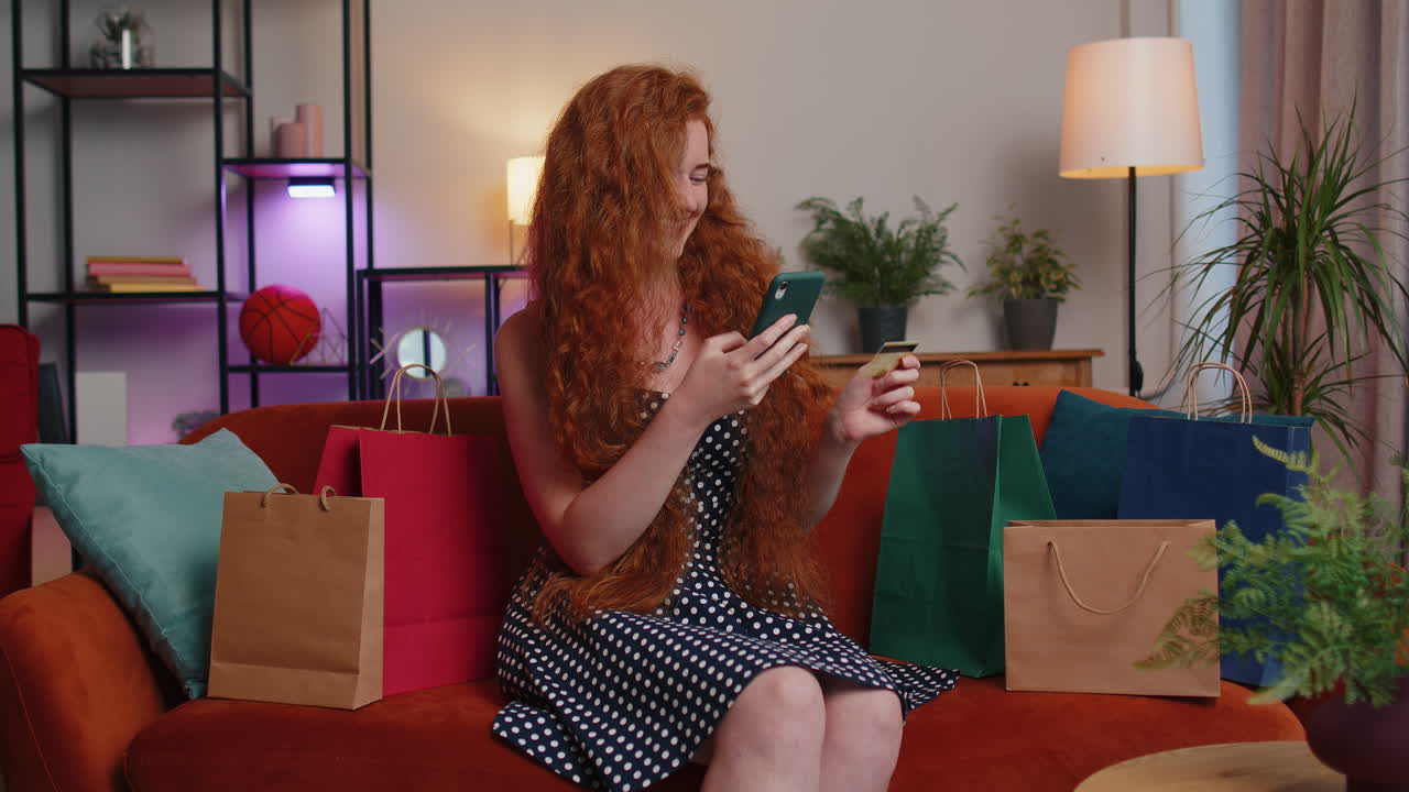 행복한 쇼핑 중독자  ⁇ 은 머리 여성이 쇼핑 가방과 함께 앉아 신용 카드로 온라인 결제를 하고 있습니다.