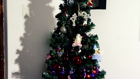 camera tilting down onto a decorated christmas tree with father christmas snowmen and magic elfes figurines laying underneath the tree