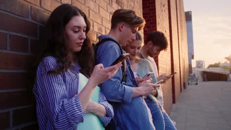 University-students-browsing-phones-next-to-university-campus-building