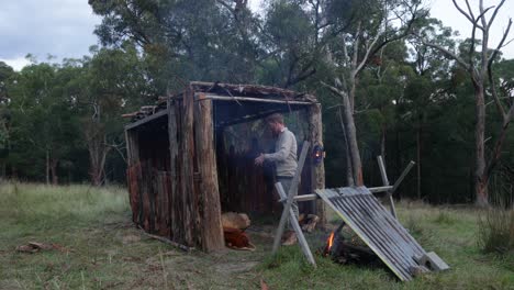 a bushman camping in a bark hut shelter in the evening in australia