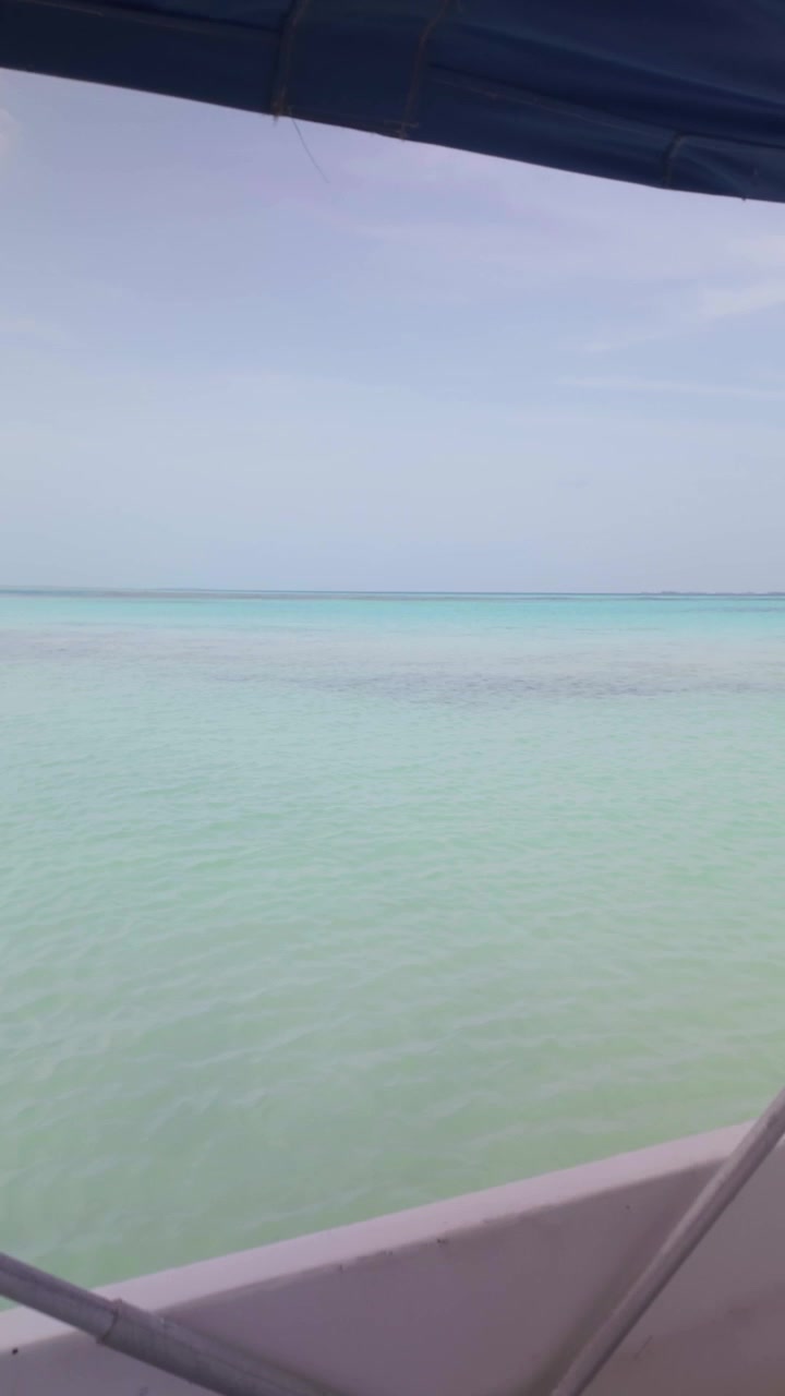 Vertical POV footage from a motorboat looking across calm turquoise Caribbean waters, capturing a serene tropical travel experience.