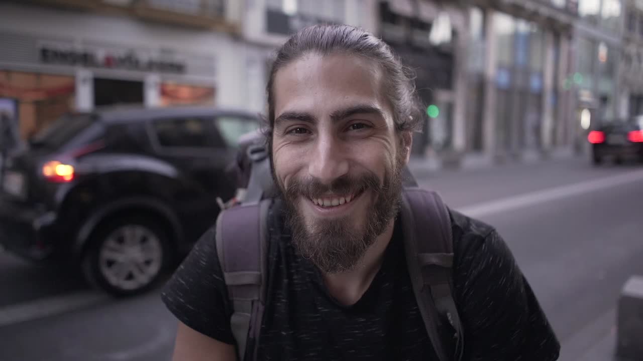 Uomo sorridente con uno zaino in strada