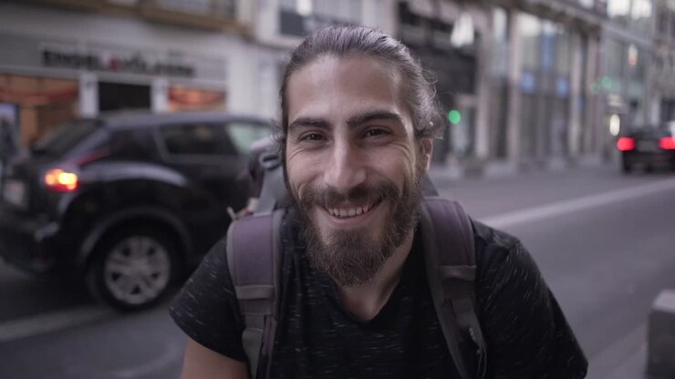 Uomo sorridente con uno zaino in strada