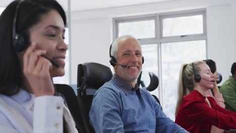 personas que usan auriculares trabajando mientras están sentadas en su escritorio en la oficina