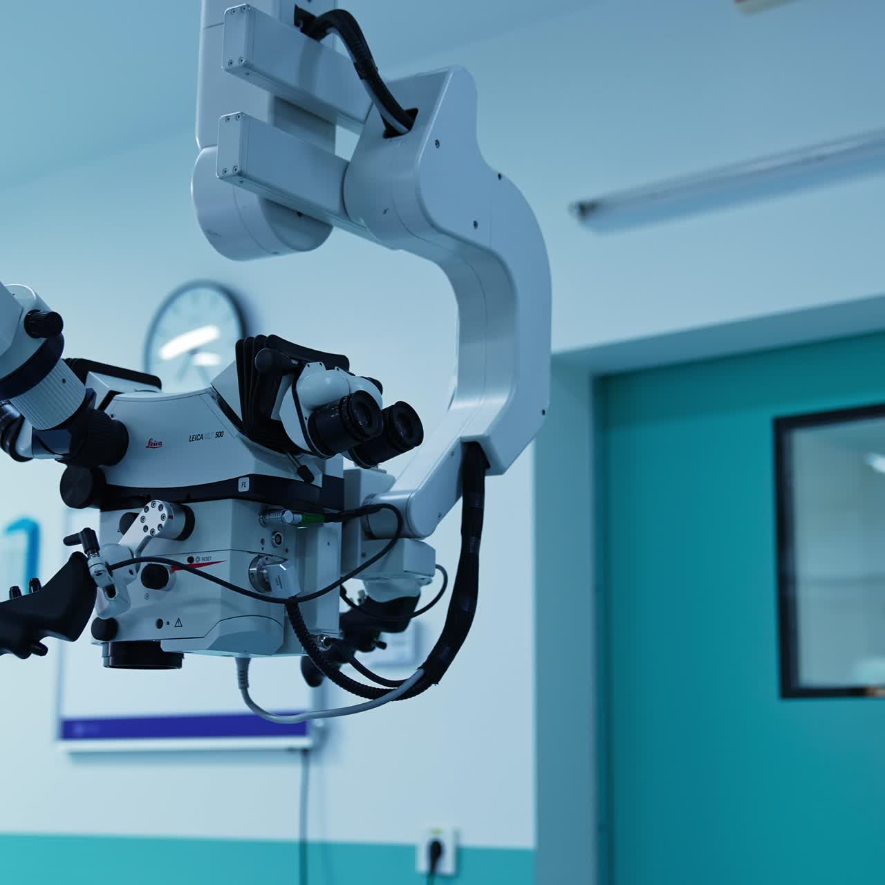 Advanced technological powerful equipment with two pairs of binoculars hanging from the ceiling. Low angle shot slowly moving from the microscope to the screen with programming panel