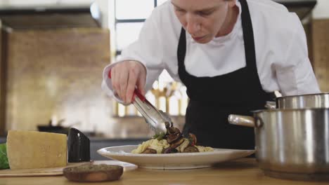 chef adding vegetables on pasta