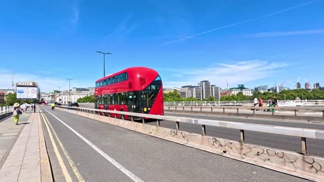 a red bus travels across a london bridge