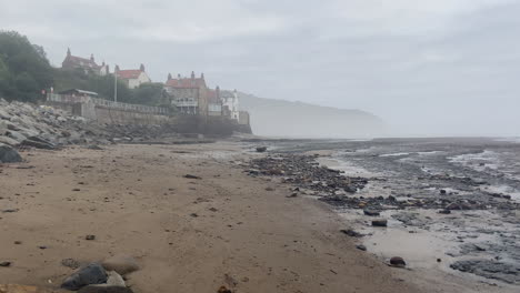 establishing handheld shot of robin hood's bay on misty morning at low tide