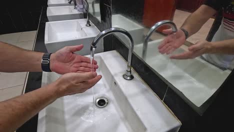 person washing hands at a public sink