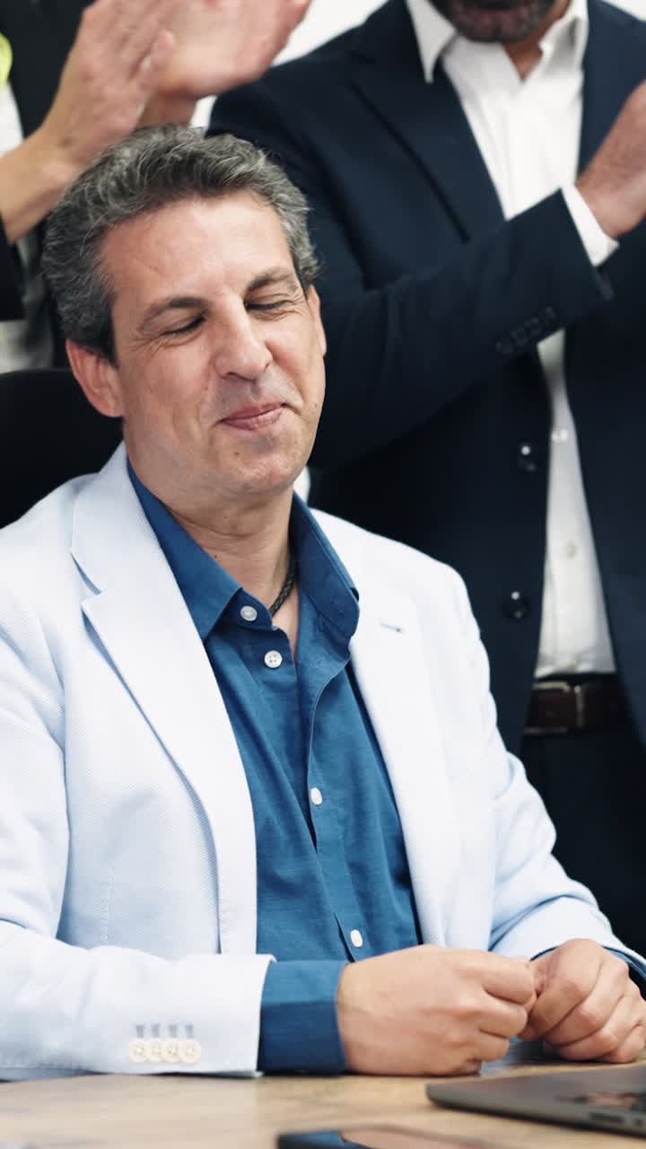 Uomo d'affari felice che celebra il successo con il team che applaude in ufficio