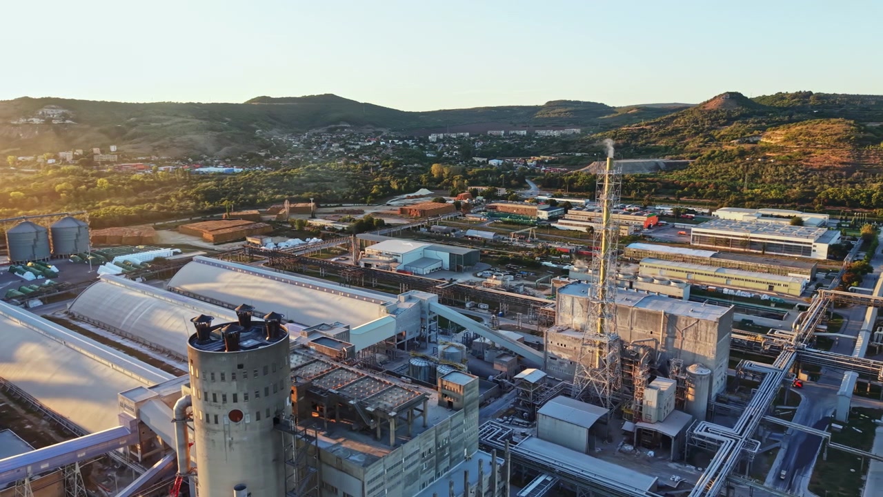 Factory site with machinery and storage facilities in a rural area during sunset