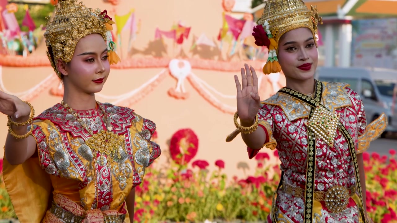 Bailarines con tocados chada dorados realizan elegantes movimientos de manos durante un festival cultural al aire libre