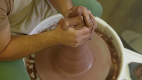 artesano hábil que forma un recipiente de arcilla húmeda girando en una rueda de cerámica