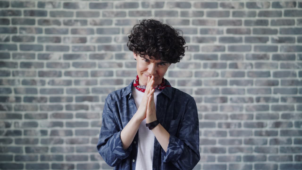 Woman with Curly Hair and Clasped Hands in Front of Brick Wall