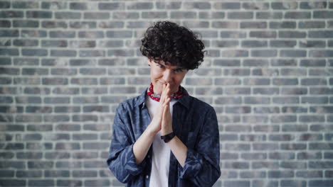 woman with curly hair and clasped hands in front of brick wall