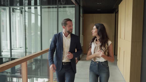 an attractive young businesswoman saludates to a young businessman who waits for her in the entrance hallway of an office building