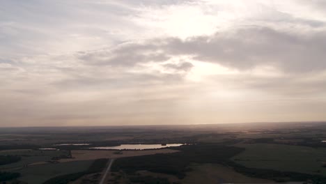 Serene-landscape-at-sunset-with-clouds-scattered-across-the-sky,-reflecting-over-calm-waters,-aerial-view