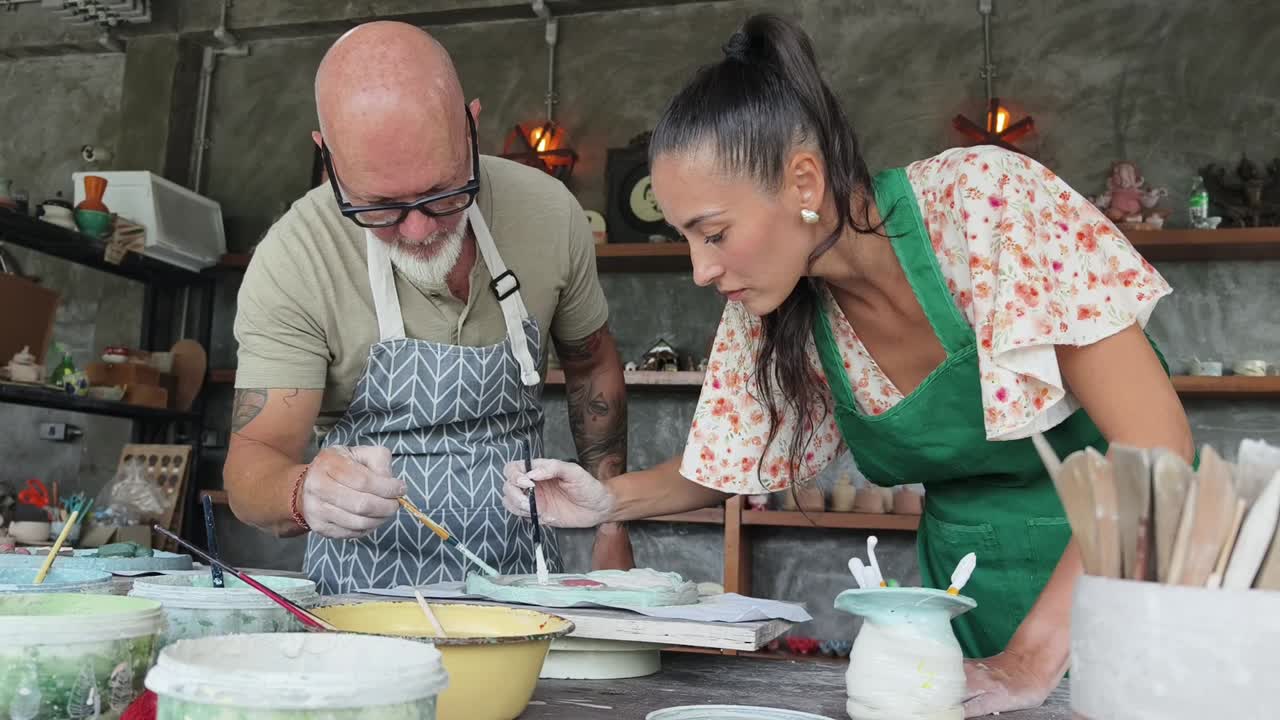 Pareja feliz pintando cerámica junta en un taller creativo