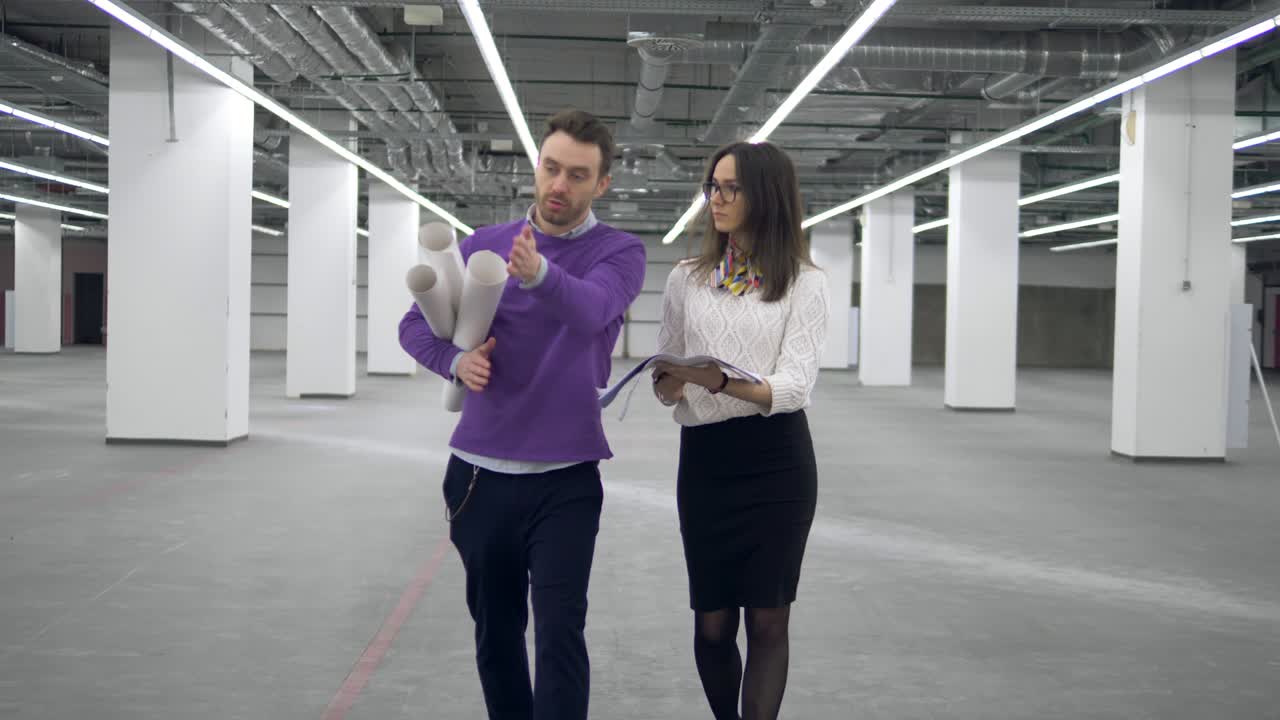 dos arquitectos están caminando por el pasillo y teniendo una conversación