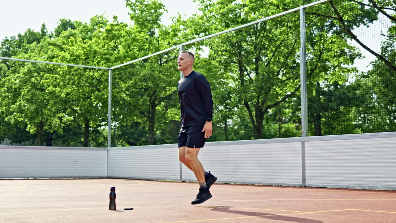 Pohledný muž v šortkách a tričku trénuje na sportovišti v parku. Muž trénuje venku. Sportovní životní styl.