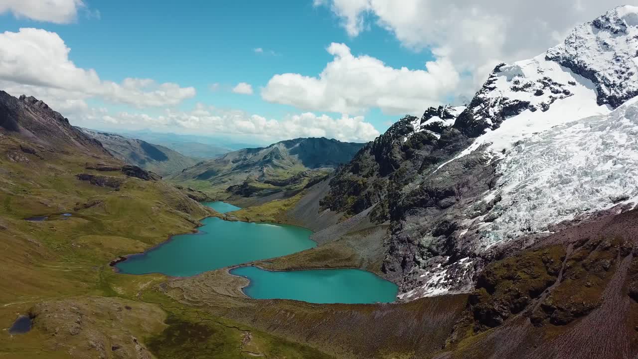 Aerial, tracking, drone shot of the twin lakes and the Ausangate Mountain and glacier, sunny day, in Andean mountains, Peru