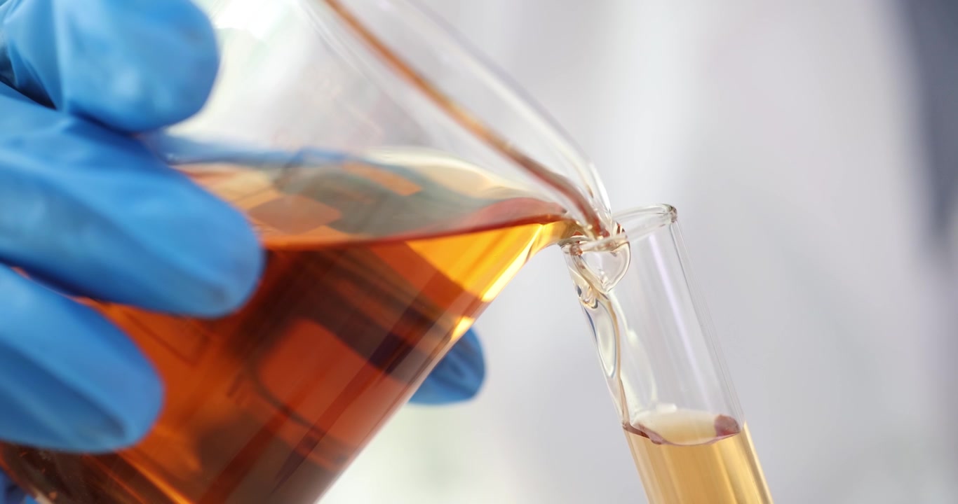 Scientist pours liquid from conical flask into test tube