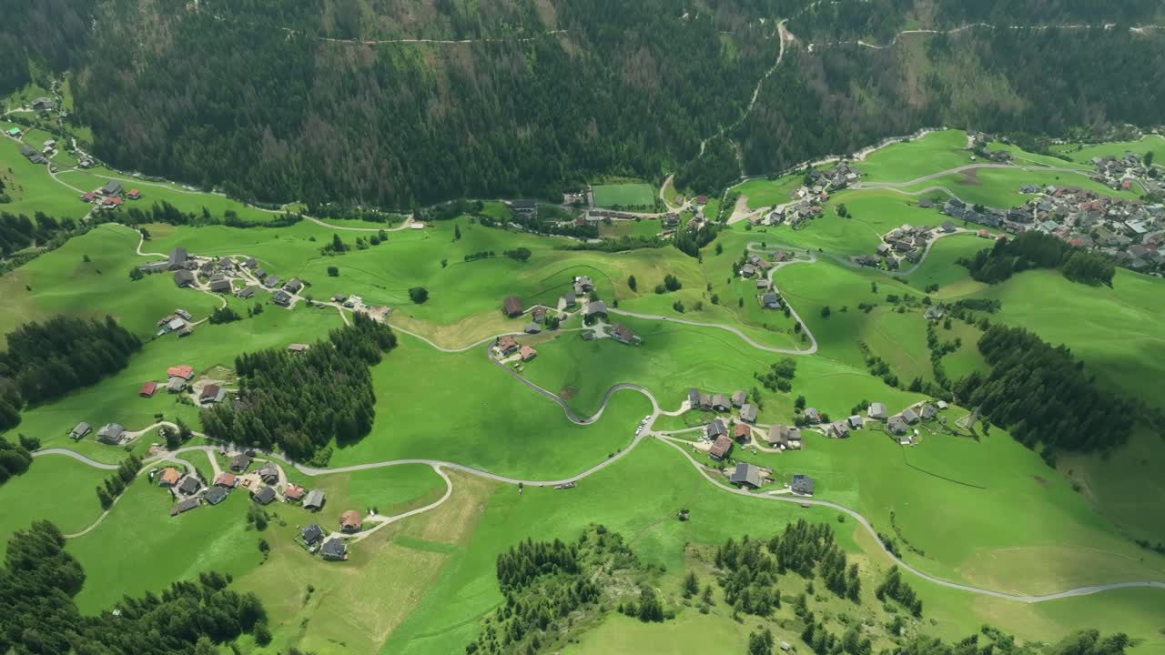 이탈리아의 돌로미트 산맥에 있는 라 발 마을의 푸른 언덕에 있는 그림 같은 농장과 도로의 영상입니다.