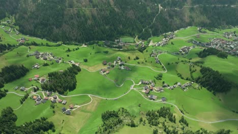 cinematic aerial overhead and tilt down footage of the picturesque farm houses and roads on the lush green hills of the la val village in the italian dolomites