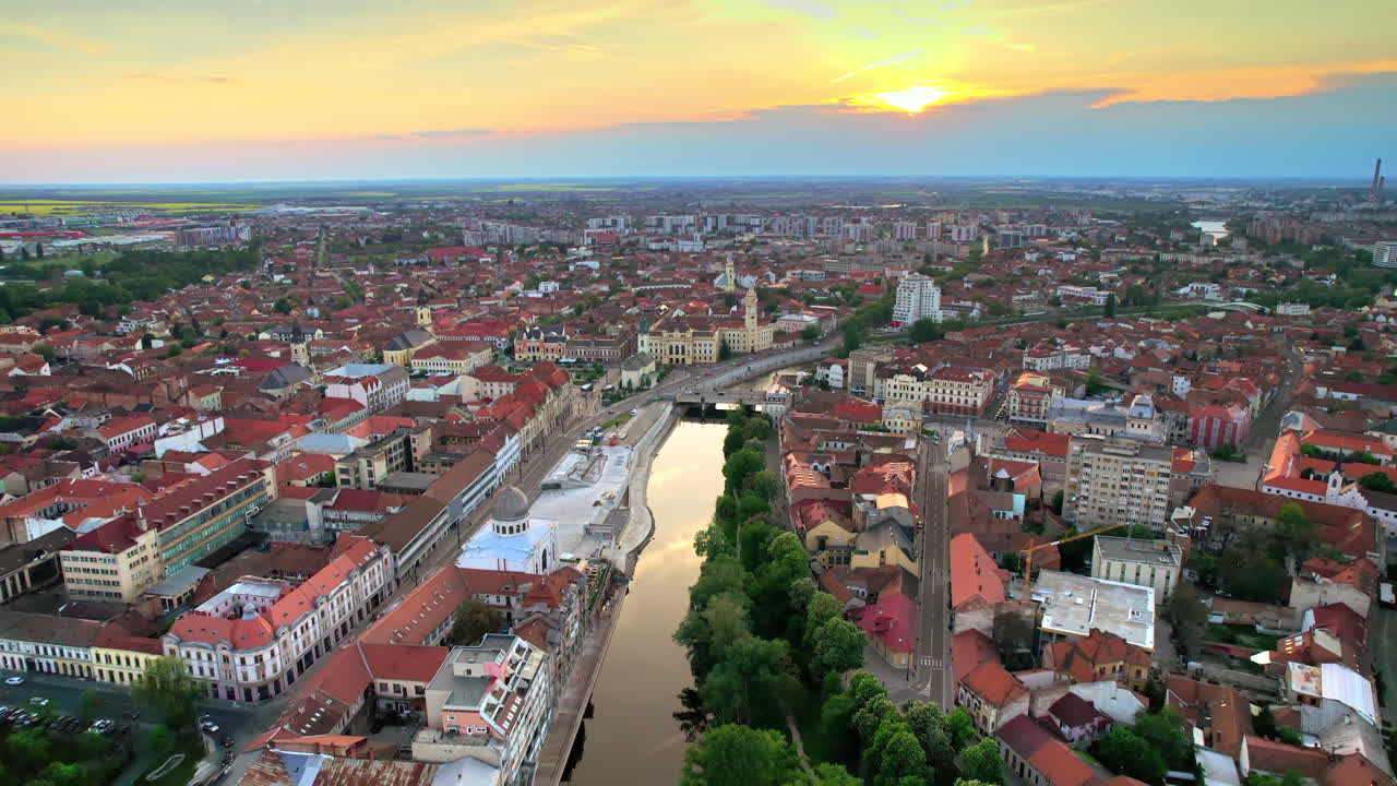 Letecký pohled na centrum Oradey při západu slunce, Rumunsko. Panorama města s mnoha historickými budovami v klasickém stylu, náměstí Unirii, řeka Crisul Repede