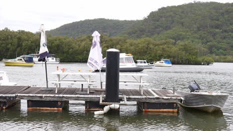 wooden jetty on hawkesbury river with a tinny boat moored up, in spencer, nsw, australia