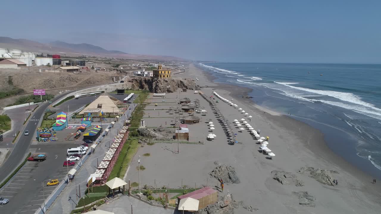 Vibrant beachfront with lined umbrellas, ocean waves, and a fun amusement area. Perfect for travel, real estate, and tourism promotion. Mollendo, Arequipa, Peru.