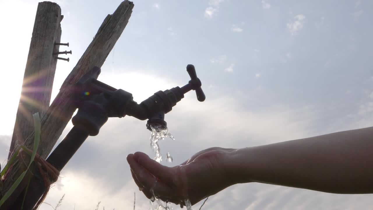 Hand cupping water coming from outside faucet tap medium shot