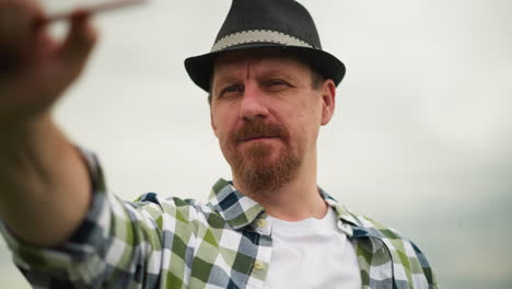 close-up view of an artist wearing a checked shirt and hat, holding a brush with his hand blurred, emphasizing his expressive face