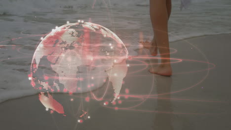 light trails over spinning globe against low section of a woman walking at the beach