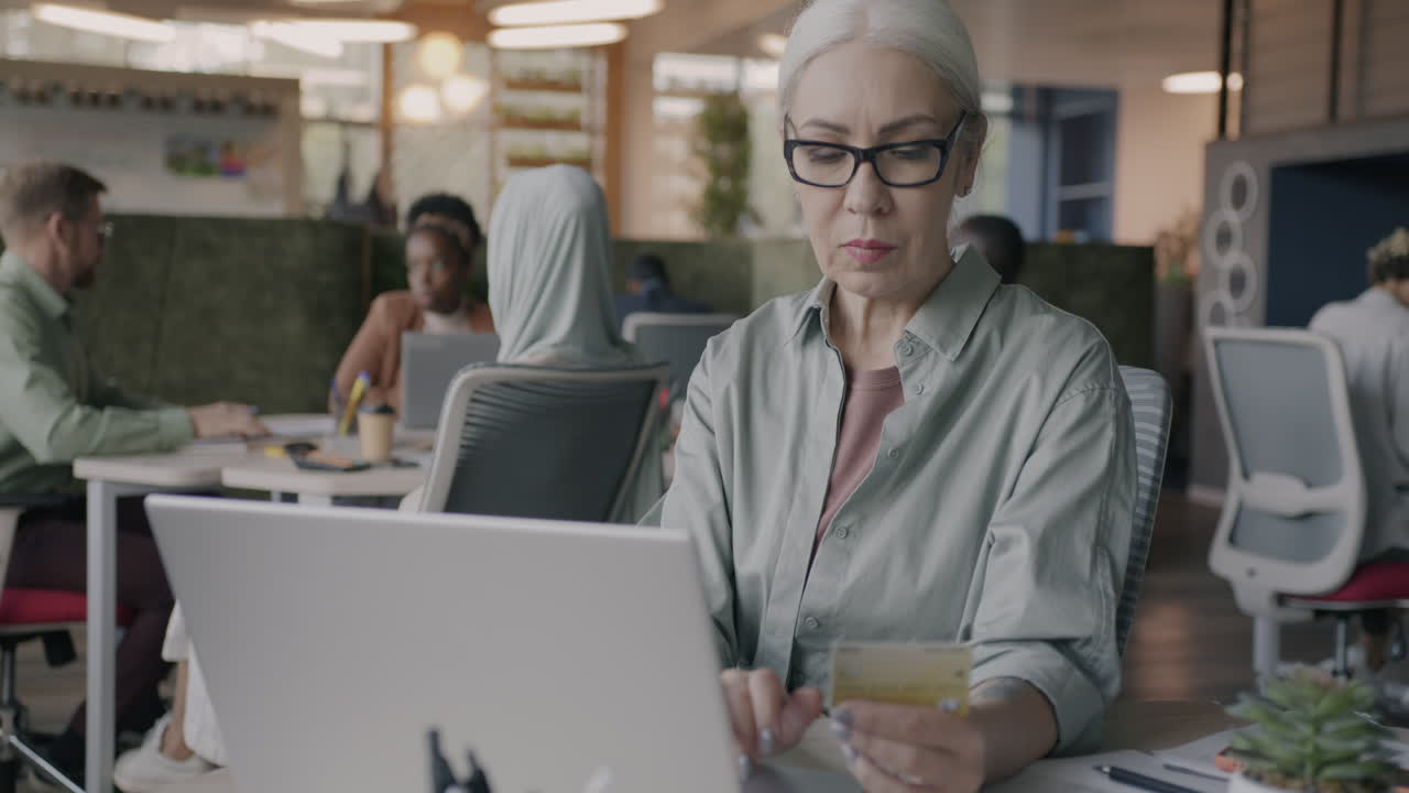 Senior Businesswoman Paying Online in Modern Office