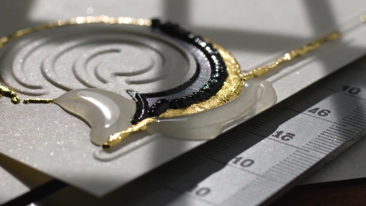 Sole che riscalda una goccia di resina trasparente, che si espande e si livella su carta glitterata, rivelando foglia d'oro e righello.