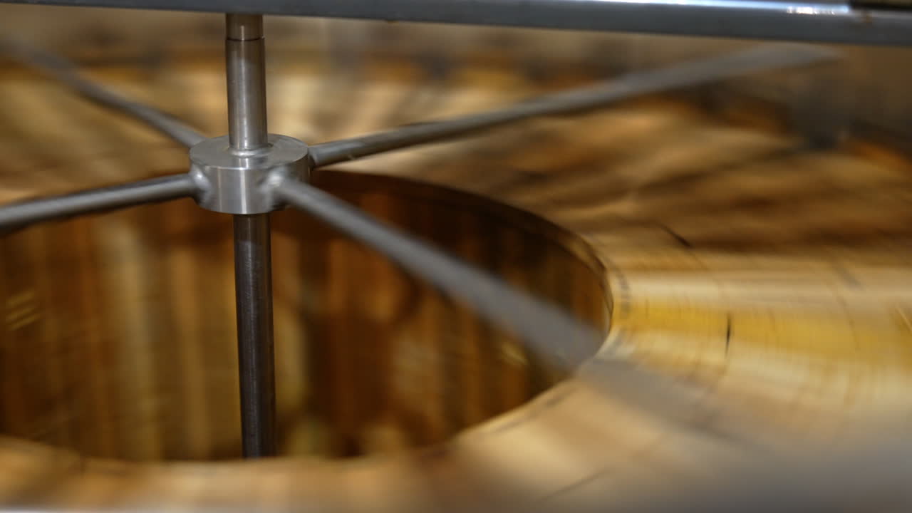 Frames with organic honey are rotated in the barrel-like centrifuge machine. Beekeepers extracting product from honey frames.