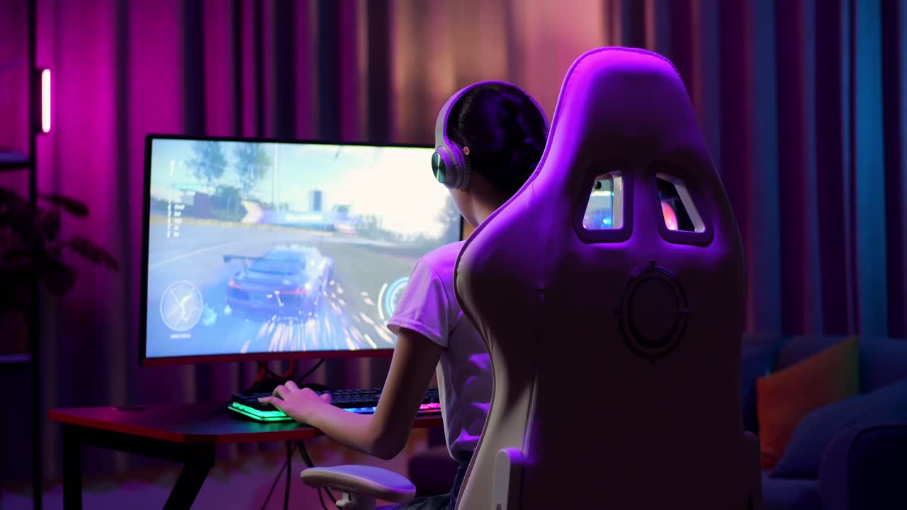Asian Teen Girl Gamer Wearing Head Phones And Playing Video Game On Computer, Playing A Racing Video Game