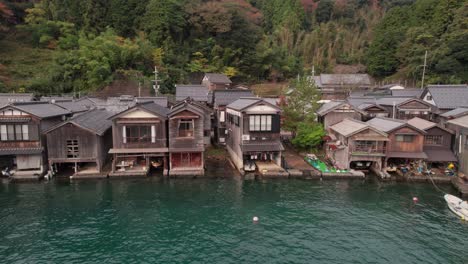 Drohnenflug-In-Zeitlupe-über-Bootshäusern-Ine-cho,-Japan,-Kyotango-Dorf,-Blaues-Meer,-Luftpanorama-Traditioneller-Holzhäuser